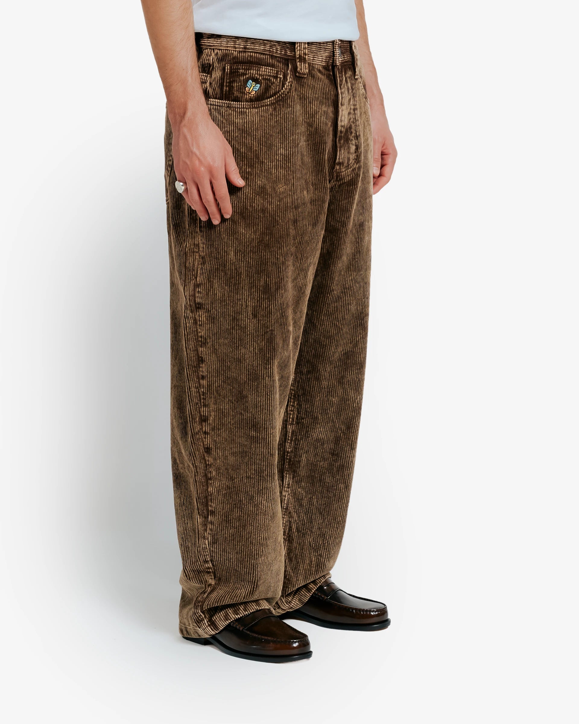 Artist Edition
Bonga is our baggy fit. It is very loose from waist to ankle, designed for comfort and a bold, laid-back look.

100% cotton corduroy for a soft, textured feel

Classic five-pocket design with belt loops
Button closure with full button fly for secure fastening

Embroidered front pocket butterfly detail&nbsp;
Bebucho design embroidered on the back pocket
Reinforced stitching ensures durability

Wide wale corduroy with bold ridges for extra texture

Unisex fit designed to suit all genders